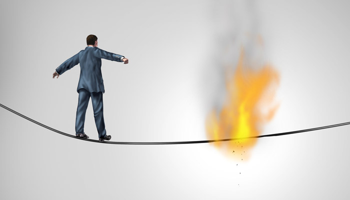 A man walking a rope that is on fire because he didn't know the new hazards that he could walk into
